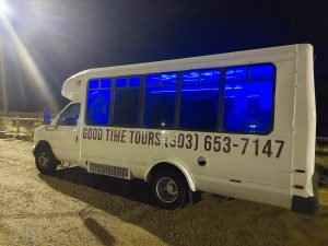 Good Time Tours Denver party bus rental at night with lights glowing inside
